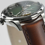 Closeup of the Hamilton Watches Jazzmaster Open Heart Auto H32675560, a men's luxury timepiece by Hamilton Watches, featuring a brown leather strap, stainless steel case, green dial, and an open-heart design that reveals the Swiss automatic movement’s internal gears.