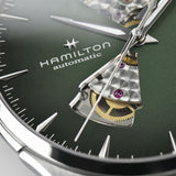 Close-up of the Hamilton Watches Jazzmaster Open Heart Auto H32675560 by Hamilton Watches, a men’s luxury timepiece showcasing a green dial, visible gears and jewels through openworked cut-out sections, and silver-tone hour markers and hands.