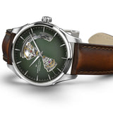 The Hamilton Watches Jazzmaster Open Heart Auto H32675560 by Hamilton Watches showcases a striking green dial, sleek silver hands, and a partial skeleton design that reveals the intricate inner gears, all complemented by a classic brown leather strap—making this Swiss automatic timepiece an exceptional addition to any men's luxury watch collection.