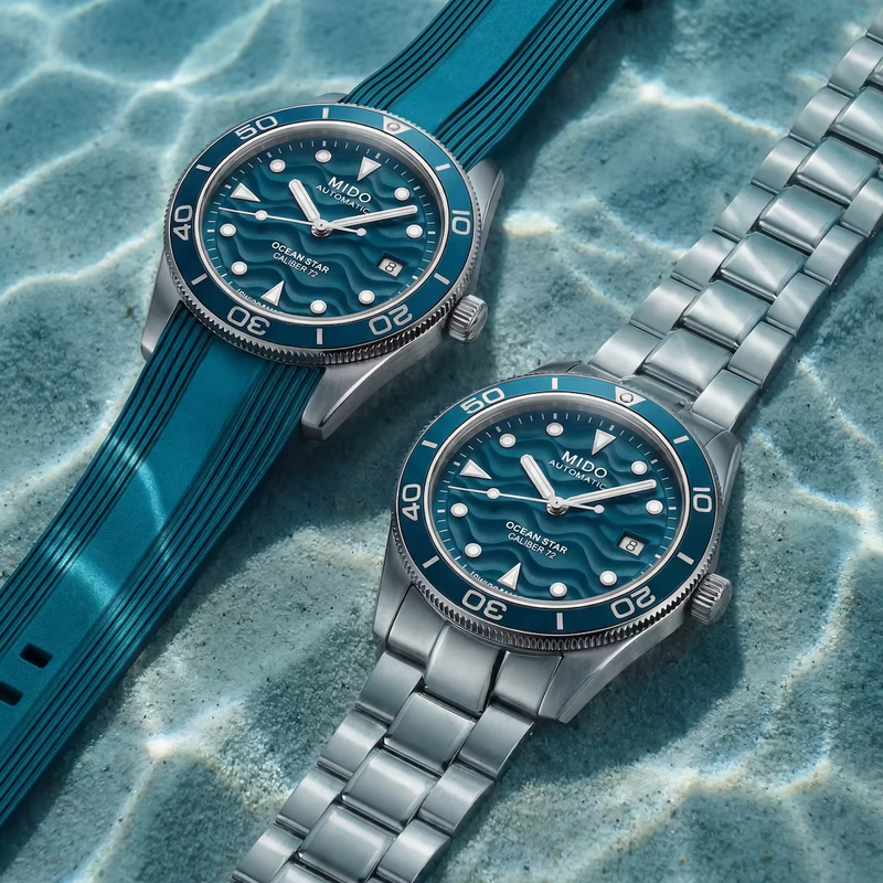 Two Mido Ocean Star 39 dive watches submerged in water, one on a blue rubber strap and one on a steel bracelet