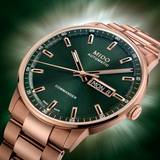 A close-up of the Mido Watches Commander Datoday M0214303309100, a Swiss automatic watch with green dial, rose gold PVD case and bracelet, day and date displays, set against a blurred green background.