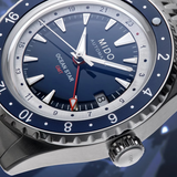 Close-up of the Mido Watches OCEAN STAR GMT (M0268291804100), a Swiss-made dive watch with a blue dial, silver hands, red-tipped GMT hand, and blue/silver 24-hour rotating bezel. The date window displays ‘8’.