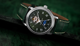 The Frederique Constant Heart Beat Moonphase Date FC-335MC4P6 is a luxury Swiss watch with a dark green leather strap, Roman numerals, open-heart mechanism, blue subdial with silver stars, and a matching green textured background.