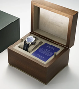 The Frederique Constant Manufacture Worldtimer FC-718LA4H6, a Swiss luxury watch with a black leather band and Lapis Lazuli dial, is showcased in an open wooden box with a blue certificate card and green box for refined elegance.
