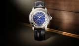 The Frederique Constant Manufacture Worldtimer FC-718LA4H6 features a blue Lapis Lazuli dial, silver case, and black leather strap, displayed on wood under soft light.