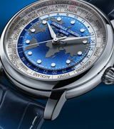 A close-up of the Frederique Constant Manufacture Classic Worldtimer FC-719BLW3H6 watch, featuring a blue textured world map dial, silver hands, city names around the bezel, and a blue leather strap against a blue background.