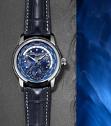 A Frederique Constant Manufacture Classic Worldtimer FC-718NWM4H6 wristwatch with a blue dial and dark blue leather strap rests on a textured gray surface beside a blue, water-like background.