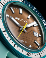 Close-up of a Bulova Watches 98B446 Snorkel (UPC 042429603509) men's dive watch with teal and brown accents, textured dial, silver markers, date at 3 o’clock, and yellow second hand, showing the time as 10:07:36.