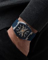 A person in a dark sweater and corduroy pants has their hand in their pocket, showcasing a Bulova Watches Maquina 98A318 automatic skeleton watch with visible gears and a bold blue strap.