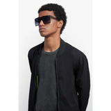 A young man with short curly hair wears Carrera Sunglasses VICTORY C 07/S 7C5, a black bomber jacket, and a dark t-shirt against a white background. Find these square shades at your Miami authorized Carrera dealer.