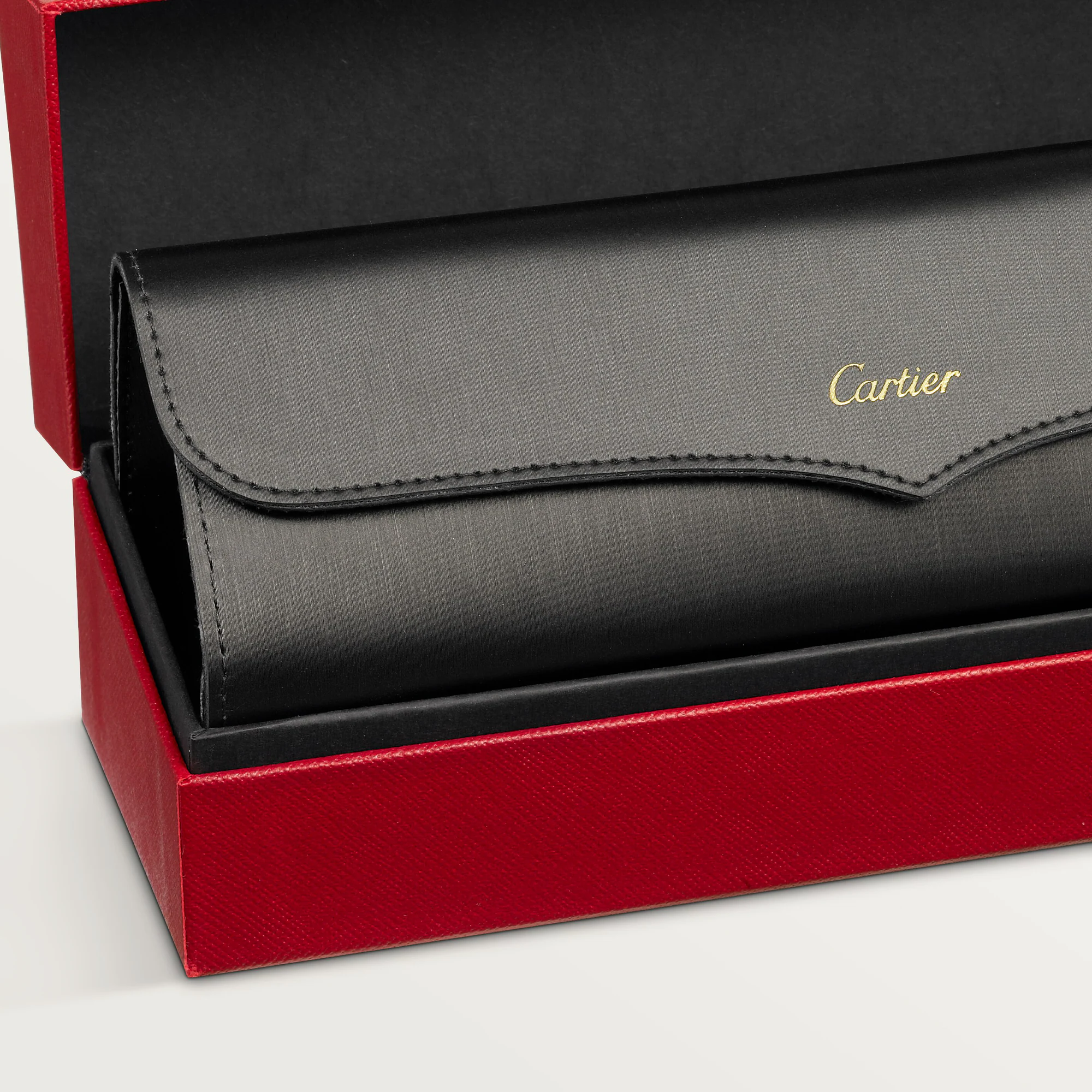 A black leather Cartier Sunglasses case with gold lettering, designed for luxury eyewear like the Cartier Sunglasses CT0550S-008 56, rests inside an open red textured box on a light background.