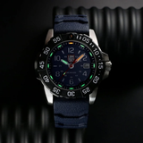 A Luminox Watches Navy SEAL Rubber, Steel, CARBONOX™ (RSC) 45 mm (SKU: XS.3253.CB) by Luminox Watches is shown with a black CARBONOX bezel, blue dial, and matching blue strap against a textured black background. The watch displays the time as 12:13, with the date window set to the 13th.