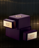 Three dark, rectangular bottles of Initio Parfums Prives Side Effect 3.0 oz EDP Perfume by Initio Perfumes are stacked atop one another against a deep, striped backdrop, capturing the allure of this luxurious and sophisticated tobacco vanilla fragrance.