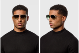 A man with short curly hair wears a black ribbed sweater and stylish Dita Sunglasses OUTRCRAFT DTS188-A-02 Unisex by Dita Sunglasses, posing for two photos—one facing forward and one in profile—against a plain light background. The tinted titanium frames of the sunglasses add a modern edge to his look.