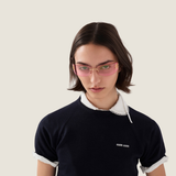 Person with straight dark hair wearing the Miu Miu Sunglasses 0MU A51S 5AK90Y75—stylish pink-tinted designer eyewear by Miu Miu Sunglasses—paired with a black sweatshirt over a white collared shirt, looking at the camera against a plain light background.