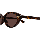 A close-up of Gucci Sunglasses GG2110S-002 54 shows their tortoiseshell cat-eye frames, dark lenses, and gold GG logo near the hinge, set against a plain light background for a modern luxury eyewear look.