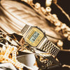 The G-Shock Watches CASIO Watch A168WG-9VT, featuring a gold metallic band, is showcased on gleaming golden surfaces with gold chains, highlighting its luxurious and elegant retro digital style.