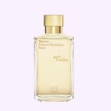 A clear rectangular bottle with a gold cap and gold label reading Maison Francis Kurkdjian Paris sits elegantly against a light purple background, showcasing the Oriental Vanilla signature of the Maison Francis Kurkdjian Gentle Fluidity Gold 6.8 EDP Sp Unisex fragrance by Maison Francis Kurkdjian Paris Perfumes.