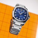 Mido Watches Multifort TV Big Date Chronometer M0495671104100 stainless steel watch with a blue square dial, featuring a large date display at the 12 o’clock position and a metal link bracelet.