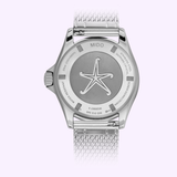 The back of the Mido M0268071104101 OCEAN STAR TRIBUTE watch by Mido Watches displays a silver case with a mesh band and showcases a starfish engraving at its center. Around the edge, text details features such as water resistance and sapphire crystal, highlighting the Swiss automatic watch craftsmanship.
