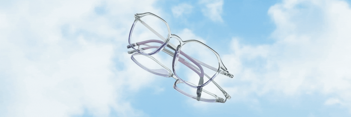 Two pairs of eyeglasses with transparent frames and light purple arms floating against a bright blue sky with white clouds.