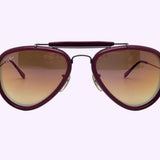 Purple-rimmed aviator sunglasses with gradient brown lenses, featuring a double bridge and the Ray-Ban logo on the left lens, are displayed against a light purple background—these unisex sunglasses are the iconic Ray-Ban 0RB3428 004/70 model from Ray-Ban Sunglasses.