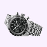 The Seiko Luxe Watches Prospex Speedtimer Mechanical Chronograph SRQ055, featuring a silver case, black dial, and tachymeter bezel, is displayed at an angle on a light purple background.