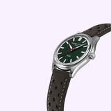 The Frederique Constant Vintage Rally Healey Automatic FC-301HGRS5B26 men's watch features a racing green dial, silver hour markers, red second hand, and a brown perforated leather strap, set against a light purple background.