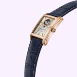 The Frederique Constant Classics Carrée FC-311S4C4-BL features a rectangular gold case, white dial with blue Roman numerals, open gear at 12 o’clock, and a blue leather strap with white stitching—showcasing classic Frederique Constant elegance.