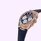 The Frederique Constant Highlife Chronograph Automatic FC-391NS4NH4 features a rose gold case, blue textured dial with three silver subdials, and black leather strap, elegantly displayed at an angle on a light purple background.