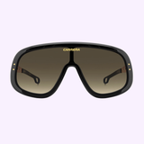A pair of large, black Carrera Sunglasses FLAGLAB 17 2M2 (UPC: 197737075071) with a thick frame and brown gradient lenses, displayed front view on a light purple background. Available from your Miami Authorized Dealer.