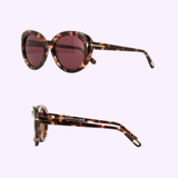Tom Ford FT1009 55 55Y Lily-02 Woman Acetate Sunglasses by Tom Ford Sunglasses feature round brown tortoiseshell frames and dark purple lenses, displayed from front and side angles on a light pastel background.