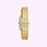 The Bulova Watches Sutton 97L177 Women’s gold-tone watch, featuring a rectangular silver back and a gold metal link bracelet, is shown vertically with its back side visible against a light purple background.