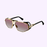 Cazal Sunglasses MOD 050 Anniversary Edition Gold-Black 001 feature gold rims, a square shape, pink gradient lenses, black arms, and side-shield details, shown on a light purple background.