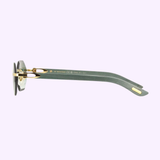 Side view of Cartier CT0439S-004 54 Woman Sunglasses by Cartier Sunglasses, featuring rimless frames, greenish-gray arms with gold accents, and round dark lenses, set against a light purple background.
