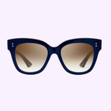 The Dita Sunglasses DAY TRIPPER 22031-D-NVY-GLD-55-Z feature oversized, thick dark blue frames and large lenses fading from dark to light brown—showcasing Japanese craftsmanship—set against a pale lavender background.