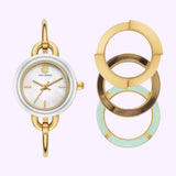 The Tory Burch Watches THE MILLER TBW6019SET Women’s watch by Tory Burch Watches, featuring a round gold and silver design, is displayed alongside three interchangeable circular bezels in gold, white, and pale green on a light background—providing a versatile watch set perfect for any occasion.