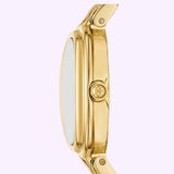 Side view of the Tory Burch Watches THE OVAL Women TBW6038, featuring a gold-tone stainless steel case with a round logo crown set against a light purple background. The watch showcases a smooth polished finish, a green malachite dial, and a metal link bracelet.
