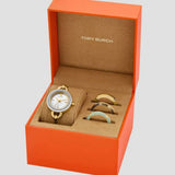 An orange Tory Burch box holds the Tory Burch Watches THE MILLER TBW6019SET Women, a sophisticated women’s watch from Tory Burch Watches featuring a gold wristband and a white face. The set includes three interchangeable bezels in gold, silver, and turquoise, making it an elegant and versatile choice for any occasion.