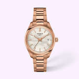 Featuring the Tissot Watches PRX 34mm T1370101135100, this elegant women’s timepiece showcases a rose gold stainless steel case and bracelet, complemented by a white dial with gold hour markers and a date display. Set against a soft light pink background, this Swiss Made watch by Tissot Watches beautifully merges timeless style with modern sophistication.
