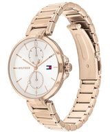 The Tommy Hilfiger 1782124 men's watch features a rose gold-tone stainless steel case, white dial with two subdials and minimalist markers, signature flag logo, and a polished bracelet with deployment clasp.