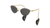 Elevate your style with Gucci GG0977S 001 57 Women Sunglasses—gold-framed cat-eye shades with dark lenses and interchangeable chains on each arm, ending in black heart-shaped charms with gold accents. From Gucci Sunglasses. Plain white background.
