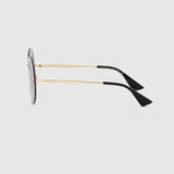 Side view of Gucci GG0899S 001 61 Women Sunglasses with round lenses, silver patterned rim, thin gold metal arms, and black curved tips, set against a light gray background. Brand: Gucci Sunglasses.