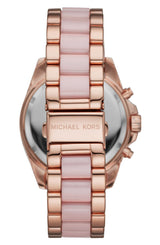 A close-up of a Michael Kors Watches MK6830 for women, showing its rose gold and pale pink link bracelet with the brand engraved on the clasp; the watch face appears partially in the background.