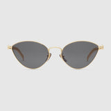 Gucci GG0977S 001 57 women sunglasses featuring gold cat-eye frames and dark tinted lenses, inspired by classic Gucci sunglasses, displayed on a light grey background.
