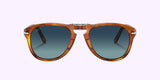 Persol PO0714SM 96/S3 54 Unisex Sunglasses by Persol Sunglasses shown from the front, featuring brown tortoiseshell frames and round blue-tinted lenses against a light purple background.