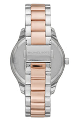 A close-up of the Michael Kors MK6849 Layton 2 Tone stainless steel women's watch shows silver outer links, rose gold central links, and "MICHAEL KORS" engraved on the clasp with a partial mother-of-pearl dial in the background.