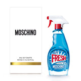 A white Moschino Perfumes box sits beside a blue glass Moschino Fresh Couture 3.4oz. EDT Women Perfume bottle shaped like a spray cleaner, with a red nozzle and Moschino Eau de Toilette written below the label.