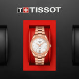 A Tissot T1019103311600 PR 100 Sport Chic rose gold stainless steel strap women’s watch with a white dial sits in a red case on a black background, featuring the Tissot Watches logo above the elegant Swiss timepiece.
