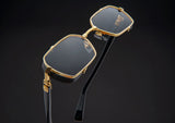 The Balmain BPS-117A-52 Brigade III Unisex Sunglasses feature gold frames, dark lenses, and black temples with gold accents—designer eyewear from Balmain Sunglasses against a plain black background.